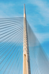 A modern marvel of engineering, the suspension bridge spans the river against a backdrop of clear blue skies, showcasing intricate cable and steel architecture