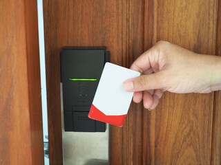 Digital door. Door access control - man hand holding white mockup key card to lock and unlock door. 