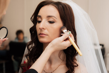 Make-up artist use brush to apply blush to the skin of girl model