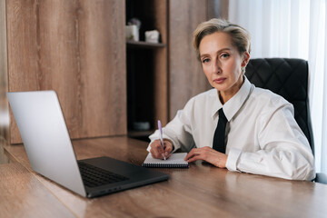 Portrait of confident middle-aged business woman using computer remote for business studying, watching online virtual webinar training meeting. Successful female entrepreneur working on laptop.