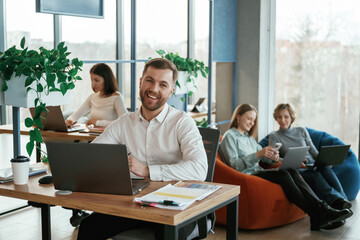 Fototapeta premium Sitting by laptops. People are working in the office with bean bags chairs in it