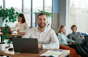 Fototapeta premium Sitting by laptops. People are working in the office with bean bags chairs in it