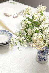 Vertical image of spring table setting with white flowers. Preparing for tea party in the garden