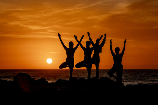 Silhouette women in Yoga Poses at Beach Sunset - Powered by Adobe