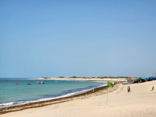 Dwarka, Gujarat India - Feb 21 2024: Shivraj Beach (Blue flag beach) - Long, flat white-sand beach with rocky outcrops and calm waves, plus wooden, grass-roofed umbrellas in Gujrat.
