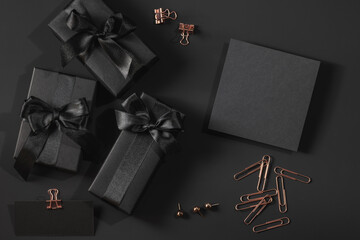 Black gift boxes with satin ribbons and a black envelope on a black background and labels. Gold...