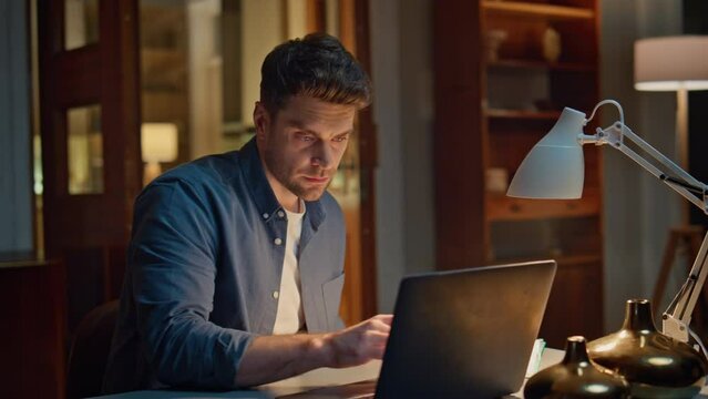 Serious accountant texting laptop night home closeup. Focused man writing notes
