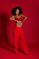 sexy appealing african american woman in red vibrant bra posing on red background and looking away