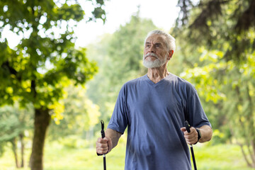 Senior man enjoying nordic walking in lush green park, healthy lifestyle concept