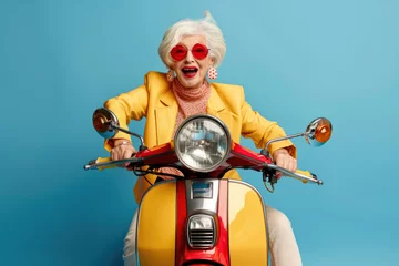 Schilderijen op glas Elegant and cheerful elderly woman in yellow jacket on bike on a blue background © Svetlana Lerie