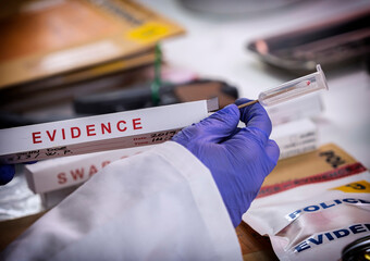 Forensic investigator holds swab of murder victim's blood in crime lab, conceptual image