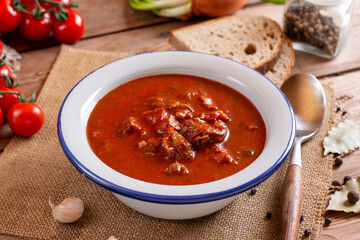 Pork goulash meat on plate, garlic, onion, tablecloth in the background - typical Czech food