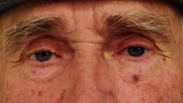 Tired eyes of a senior caucasian man. Close-up of an elderly wrinkled man's eyes. Wise look of an old grandfather. Grandparents day concept.