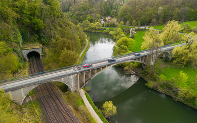 Cars driving on the bridge over the river and the train tracks in the German countryside 