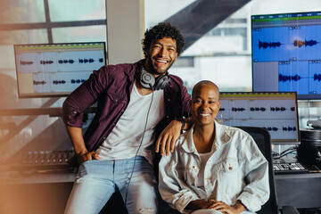 Happy sound engineers in recording studio with audio editing software