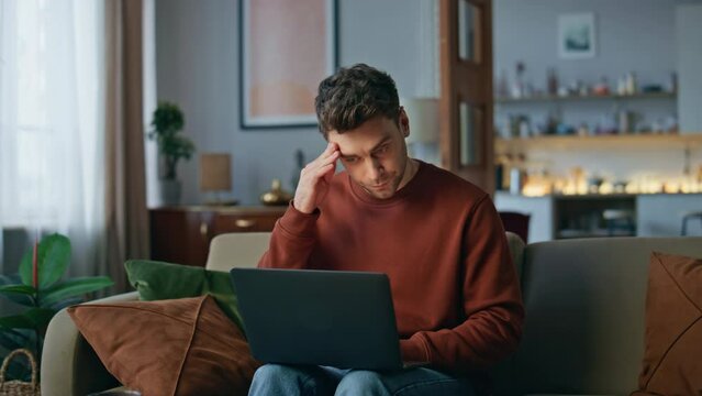 Worried freelancer typing laptop screen at sofa. Online worker working remote