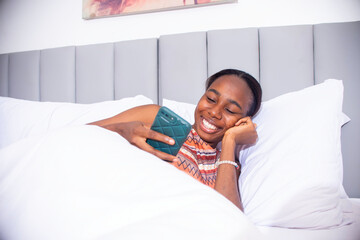 young black woman using her phone in bed