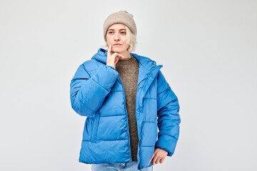 Woman in winter attire with a pensive expression, isolated on a light background.