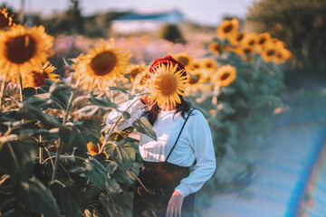 A young woman covers her face with a sunflower.