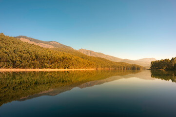 Beautiful, calm lake flanked by trees and mountains in Munnar, Kerala, India.