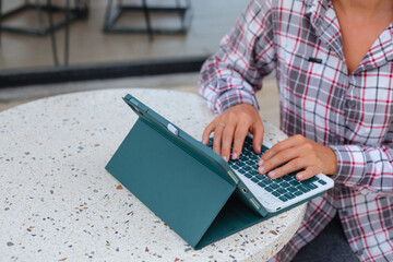 Woman sitting at table and typing on tablet. Female blogger blogs on the internet. Blogger Posts on...