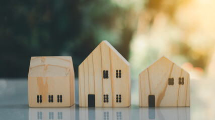 Miniature model of the house. Three wooden homes on the table with a green nature background. Home sweet home. Rent, buy, or sell real estate.