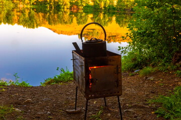 boiling kettle on a camp stove in the forest against the backdrop of mountains