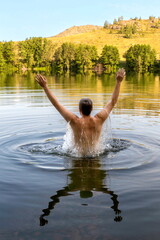 a young man swims in a beautiful lake against the backdrop of the Ural Mountains in the early morning