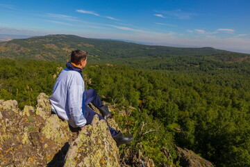 a young man rests on the rocks in the mountains of the Southern Urals on a summer sunny day