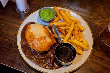 Edinburgh UK: 16th Feb 2023 Traditional steak and ale pie and a pint in a Scottish pub with chips,...