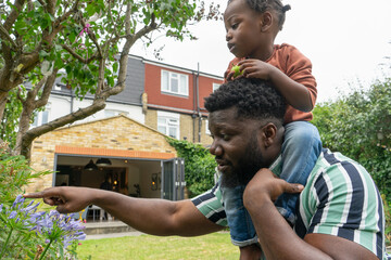 Father giving daughter (2-3) piggyback ride in garden