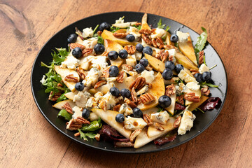 arugula or rocket pear and blueberry salad with gorgonzola blue cheese and pecan nuts