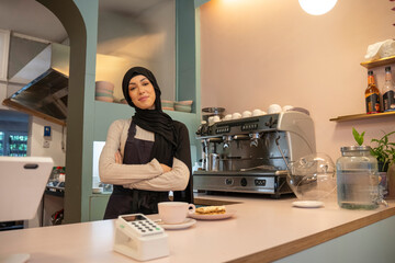 Portrait of young woman in hijab working in cafe