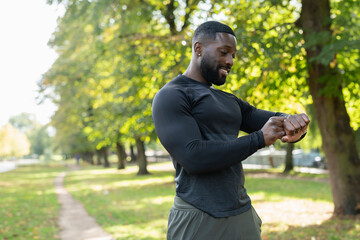 Smiling athletic man checking smart watch in park