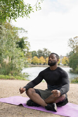 Naklejka na ściany i meble Athletic man meditating in park