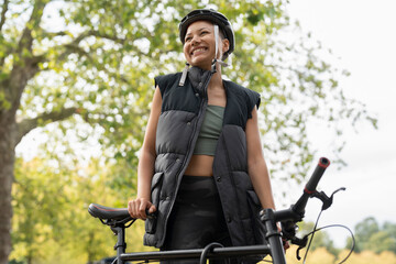 Fototapeta na wymiar Smiling woman wearing bike helmet in park