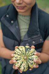 Mid section of woman holding homegrown gourd in urban garden