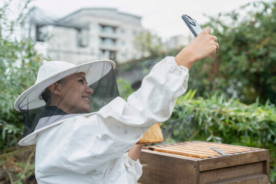 Smiling female beekeeper taking selfie in urban garden