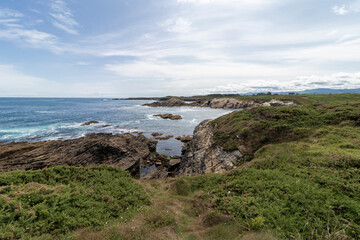 Fototapeta na wymiar rocky cove surrounded by green field on the coast of asturias in summer