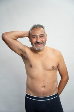 Portrait of smiling senior man without shirt against gray background