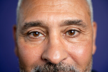 Close-up of man looking at camera against purple background