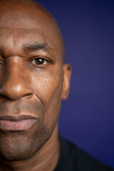 Portrait of serious man looking at camera against purple background