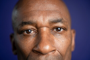 Close-up o serious man looking at camera against purple background