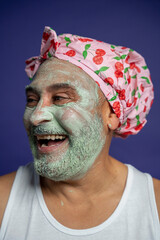 Portrait of man in facial mask and hair cap against purple background
