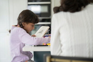 Obraz na płótnie Canvas Little girl doing homework with sister