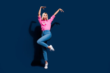 Full body photo of adorable satisfied woman wear stylish shirt denim trousers hold hands up dancing isolated on dark blue color background