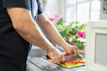 Midsection of man chopping vegetables in kitchen - obrazy, fototapety, plakaty