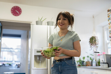 Young woman preparing food in kitchen - obrazy, fototapety, plakaty