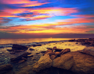 Seascape in the evening with a beautiful dramatic sunset sky. Wild rocky beach in the evening