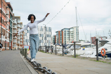 Smiling woman balancing on chain link in city